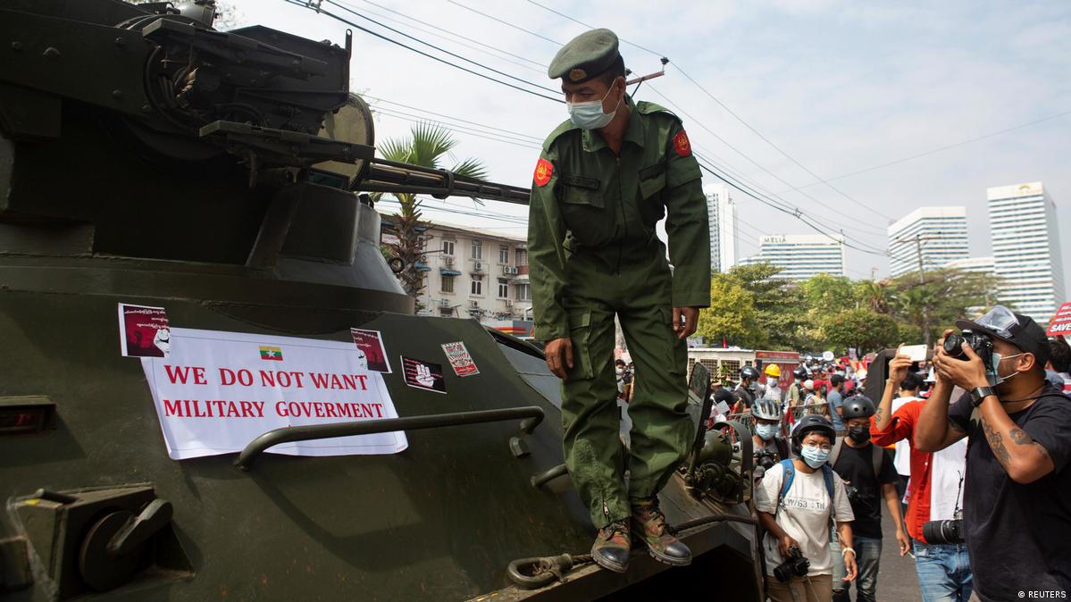 အာဏာသိမ်းကာလအတွင်း ၂၀၂၁ ခုနှစ် ဖေဖော်ဝါရီ ၁၅ ရက်နေ့က ဗဟိုဘဏ်အပြင်ဘက်ရှိ စစ်ယာဉ်တစ်စီးတွင် ဆန္ဒပြသူများ ကပ်သွားသောစာတန်းကို မြန်မာစစ်သားတစ်ဦးက ကြည့်ရှုနေစဉ်။ ဓာတ်ပုံ - Reuters